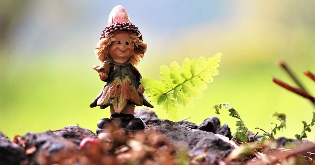 Troll names - A cute troll girl figurine in a forest with fall leaves