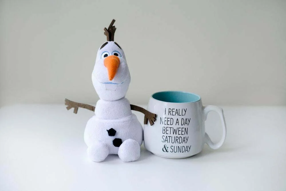 Famous snowman names - Olaf Frozen snowman toy with a coffee mug with text I really need a day between Saturday & Sunday
